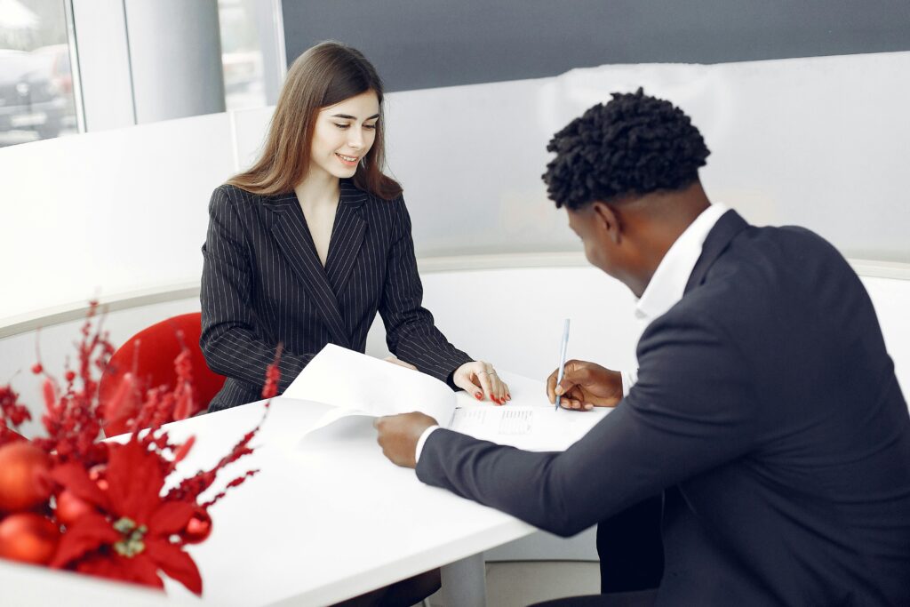 A professional setting with two business people signing a contract in an office environment.